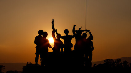 Fototapeta na wymiar silhouette group of special forces sodiers hold the guns on tanks to indicative of their victory with the sunset background