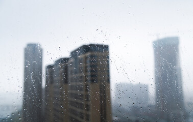 City buildings through a window with water drops