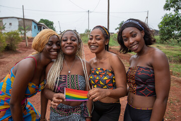 Group of smiling African lesbian girls together with the rainbow flag get together, LGBTQ + in africa - obrazy, fototapety, plakaty