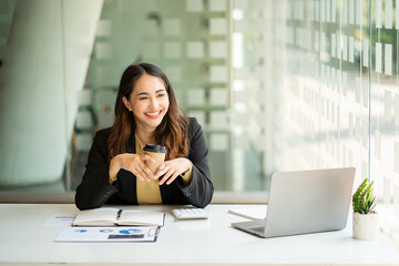 Young Asian businesswoman doing bookkeeping Finance Graph uses laptop while doing homework video calling abroad using friend internet connection business women use computers to analyze financial data