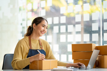 Asian woman working with box and laptop at home at work Starting a small business owner Entrepreneurship, small business, SME or freelance online and delivery ideas.