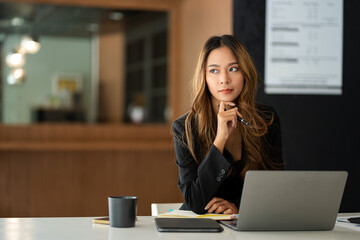 Young Asian businesswoman doing bookkeeping Finance Graph uses laptop while doing homework video calling abroad using friend internet connection business women use computers to analyze financial data