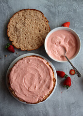 Strawberry cake in process. Close up photo of strawberry tart ingredients on a table. Fresh berries, dairy cream, cake layers top view. 