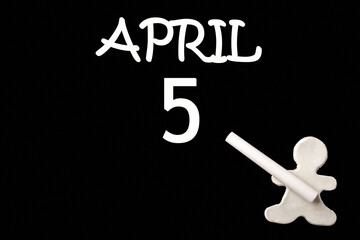 A small white plasticine man writing the date 5 April on a black board. Business concept. Education concept.