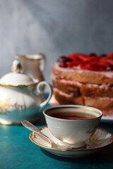Vintage cup with black tea, strawberry cake and fresh berries on textured background. Sweet food still life. Birthday cake close up photo. 