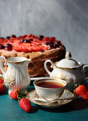 Vintage cup with black tea, strawberry cake and fresh berries on textured background. Sweet food still life. Birthday cake close up photo. 