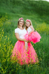 Portrait of a daughter hugging mother on nature on summer day vacation. Mom and girl walk in the park. Happy young family spending time together. Concept of friendly family. Close Up.