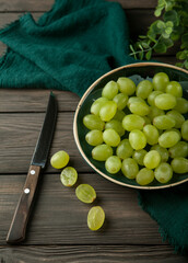 grapes on a ceramic plate with knife on wooden table