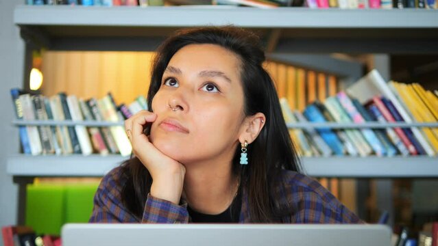 Young woman working on laptop at the library. Concept of new idea, imagination, freelance, online studying. High quality 4K slowmotion portrait.