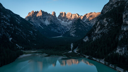 Alpenglow of Lake Lago di Landro at Toblach with mountain chain reflecting on water surface during...