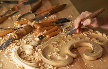 Wood carving, master's hands work with a wooden surface, a professional does wood crafts