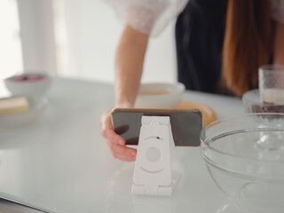 Young woman looks at a recipe for cooking a pie in a smartphone. food tutorial or cooking courses online. Baking dessert concept.