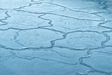 A large ice surface with odd shaped cracks or frazil ice in a harbor. The cold winter temperatures...