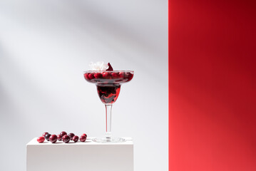 Cóctel margarita de arándanos rojos sobre un soporte blanco y fondo gris	