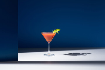 Bloody Mary decorado con hoja de apio en copa de cóctel sobre fondo azul	