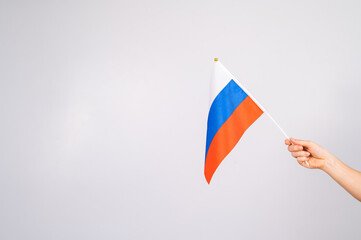 Woman holding a small flag of the Russian Federation on a white background. 