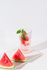 Un vaso de zumo de sandía con trozos de sandia y hielo sobre fondo claro	