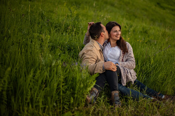 A loving couple lies and makes love among the lawn at sunset. Copy space.