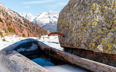wooden mountain drinking fountain in winter with water coming out of a rock