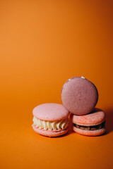 Close-up of macarons cakes of different colors in orange background. Culinary and cooking concept. Tasty colourful macaroons.