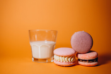 Pastel color macaroons and a cup of milk on vintage light blue wooden background