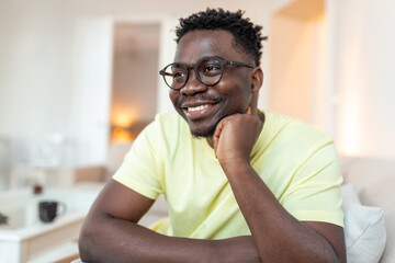 Profile picture of smiling young African American man in glasses pose in own home apartment. Close...