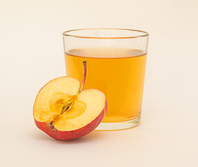 a glass of apple juice and a half of red apple isolated on white background.