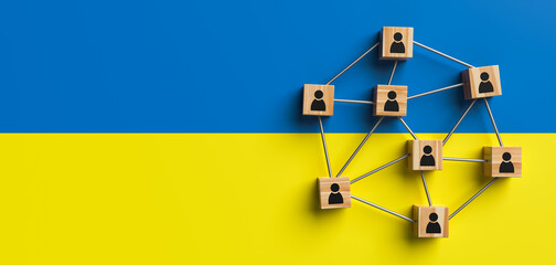 Wooden blocks with people icon on the background of Ukraine flag. Concept of unity and solidarity of people. Copy space. 3d rendering.