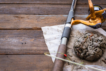 Fishing rod and fishing bait on the brown wooden table background with copy space.