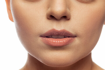 Fototapeta premium Cropped close-up image of female lips, cheecks and nose isolated over white studio bacground