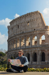 Young tourist sitting in front of the Roman Colosseum looking at the city map