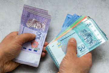 Malaysian money held in both hands, Lots of ringgit, Gray background, Financial business concept