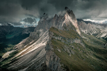Dramatic mountain peaks of Seceda with clouds in the European Dolomite Alps, meadow in the foreground, steep cliff, South Tyrol Italy.