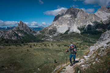 Man hiking along trail to Croda Negra mountain summit at Passo di Falzarego during sunny blue sky day in the Dolomite Alps, South Tyrol Italy.