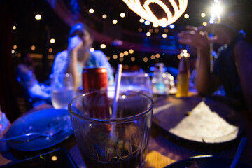 closeup fisheye distorted drunk shot showing drink whiskey gin tonic with blurred people in...