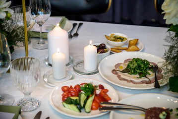 Wedding banquet. The festive table is served with plates with napkins and name cards, glasses and cutlery, and decorated with flower arrangements and candles