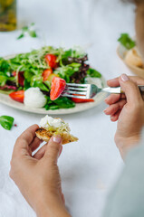 Salad with strawberries, cherry tomatoes and mixed salad. Woman tasting salad with a fork.