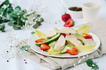 Healthy salad with chicken breast, avocado, lettuce, strawberries and parmesan cheese. A light and nutritious summer salad.