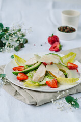 Healthy salad with chicken breast, avocado, lettuce, strawberries and parmesan cheese. A light and nutritious summer salad.