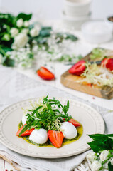 Light summer fresh salad. Buffalo mozzarella with strawberries, pesto, arugula and lettuce.