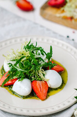 Light summer fresh salad. Buffalo mozzarella with strawberries, pesto, arugula and lettuce.