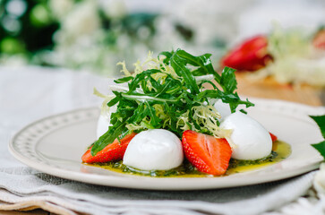 Light summer fresh salad. Buffalo mozzarella with strawberries, pesto, arugula and lettuce.