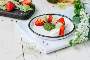 Caprese salad with strawberries. Mozzarella with strawberries, pesto and lettuce.