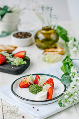 Caprese salad with strawberries. Mozzarella with strawberries, pesto and lettuce.