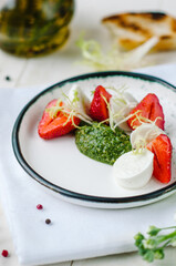 Caprese salad with strawberries. Mozzarella with strawberries, pesto and lettuce.