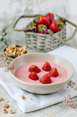 Natural strawberry yogurt with strawberries in bowl and granola. Healthy breakfast on a light background in rustic style.