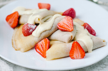 Summer sweet breakfast with french pancakes with strawberries and vanilla sauce. Сlose-up
