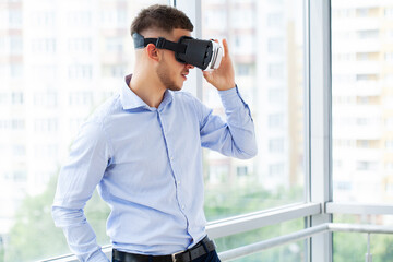 Man in office clothes and virtual reality glasses touching air.