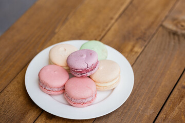 Macaroons in a plate on a background of cafes. Macaroons on a wooden table.