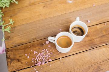 Espresso coffee on a wooden table. Coffee in a small cup. Good morning. Coffee on the table with pink crumbs.